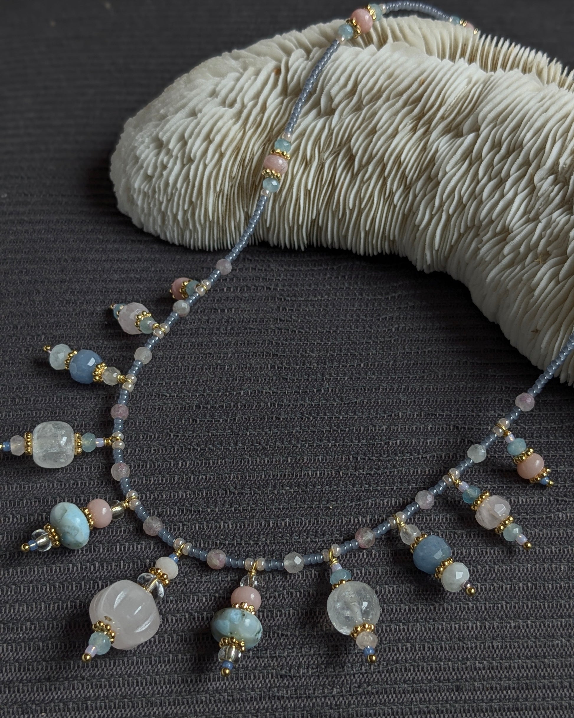 Zoom sur le quartz rose sculpté et les rocailles japonaises scintillantes du collier Prishaara.