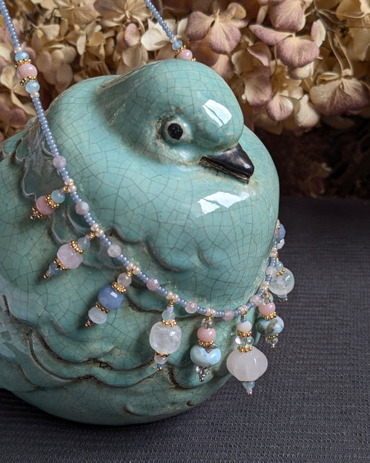 Collier Prishaara 49 cm en pierres fines : quartz rose sculpté, larimar, opale rose, quartz rose, cristal de roche, aventurine bleue, jade bleu et mauve, ponctué de rocailles japonaises bleu givré.
