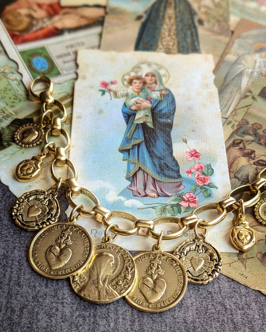 Bracelet Sacrement par Mudra, une parure ex-voto au plaquage doré ornée d'une accumulation de 9 médailles religieuses et symboliques sur une maille texturée.