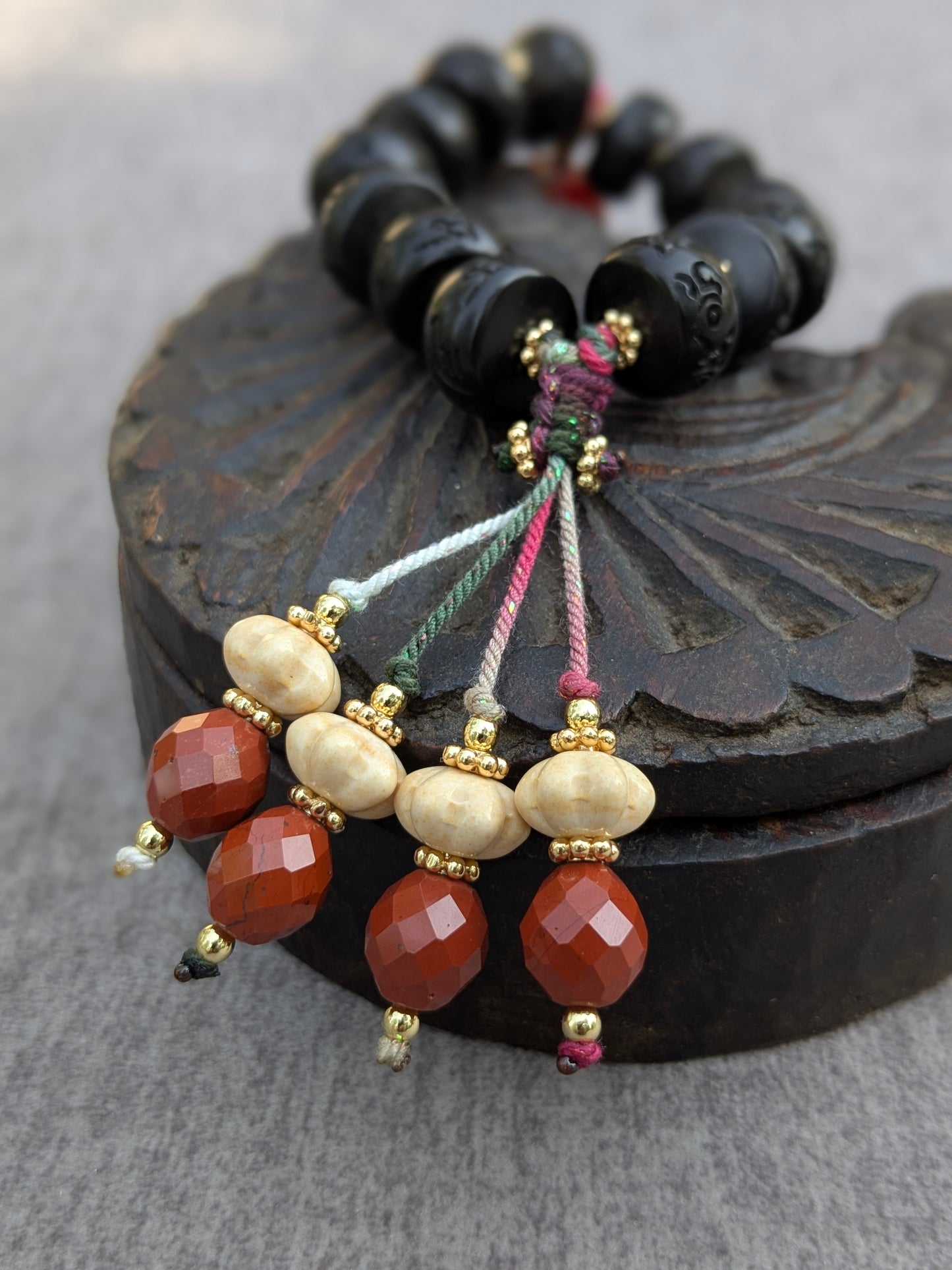 Détail des pampilles du bracelet Dolma Mudra en agate et jaspe rouge sur cordons torsés multicolores