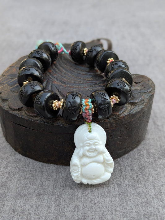 Bracelet Jampa Mudra, perles en bois de jujube gravées du mantra Om Mani Padme Hum, posé sur une boîte ancienne avec pendentif Budai en coquillage blanc