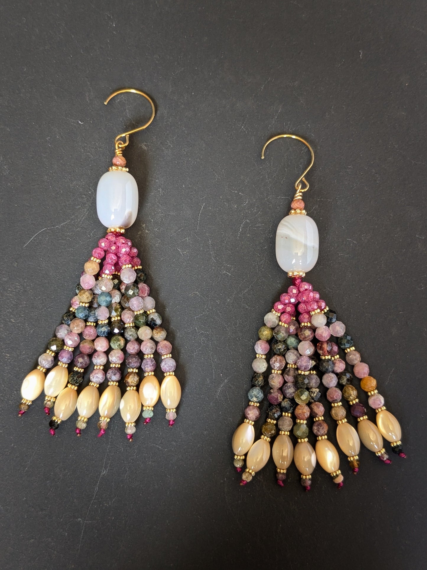 Paire de pendants d'oreilles Kiara Mudra posés sur un présentoir, calcédoine blanche et tourmaline multicolore