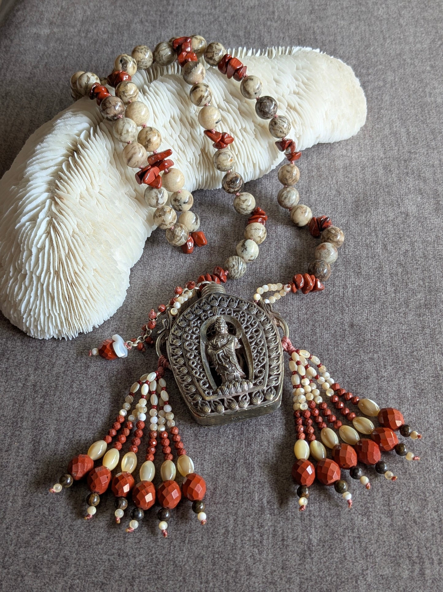 Collier Guanyin noué, longueur et pendentif flacon visibles sur corail blanc