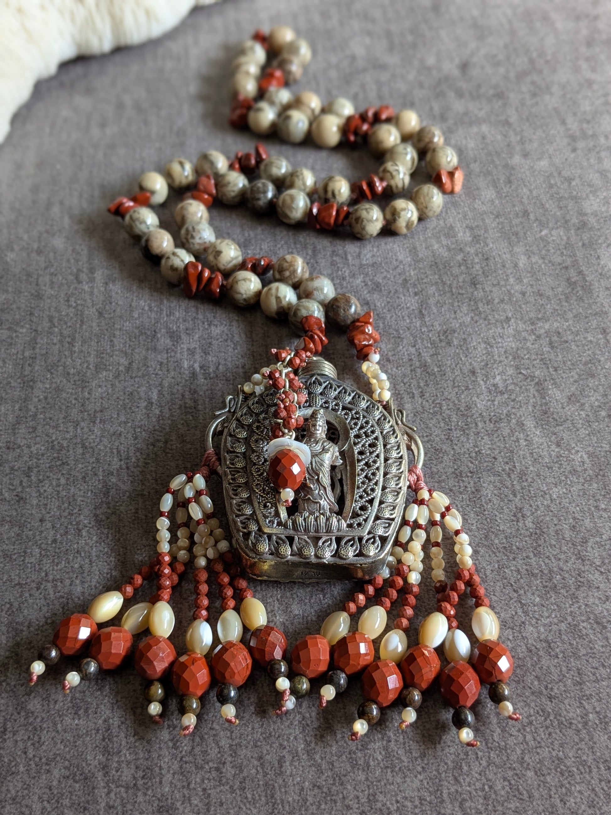 Vue rapprochée du pendentif Guanyin avec les deux tassels nacre et jaspe rouge