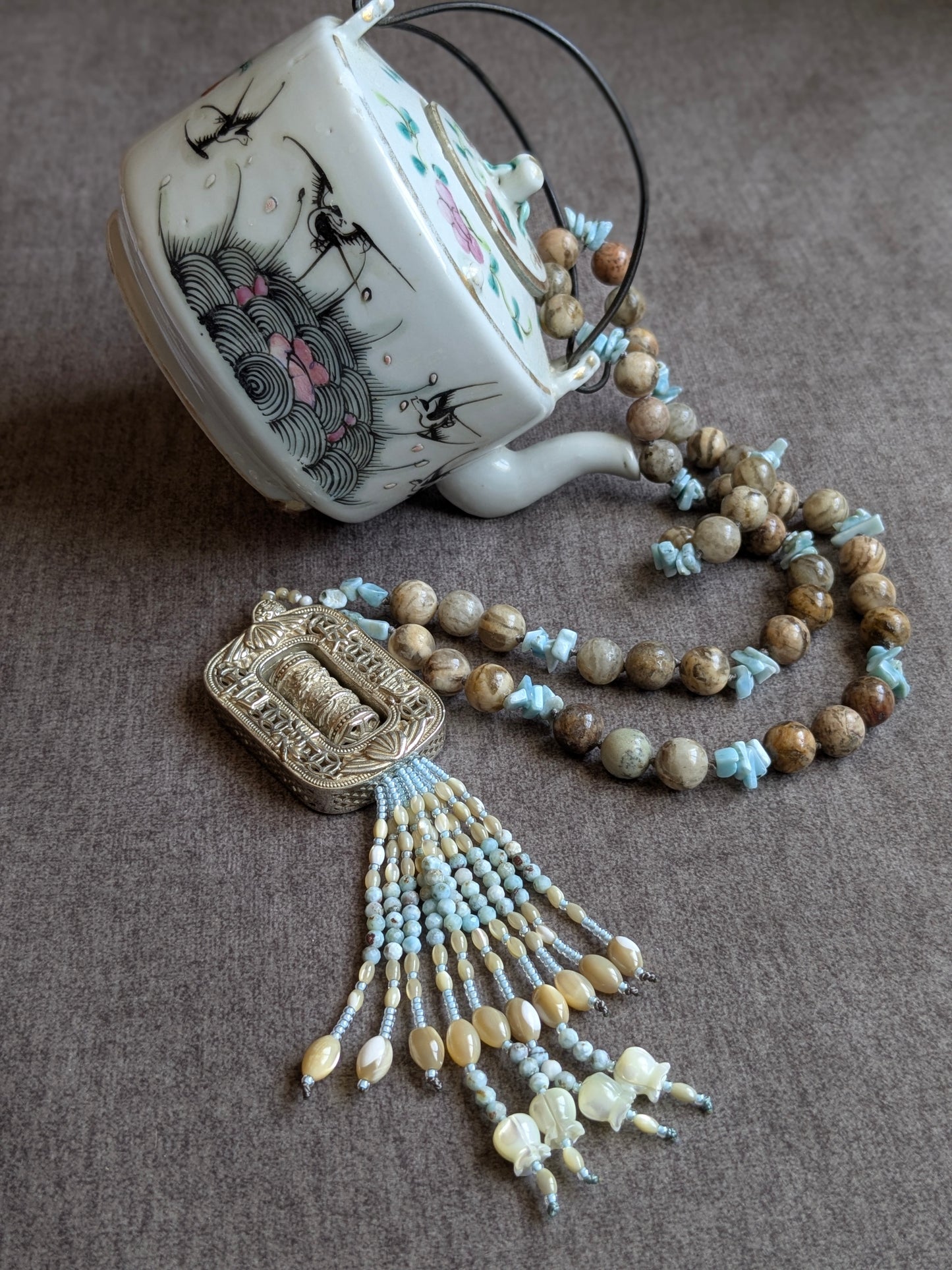 Collier Mani noué avec pendentif moulin à prières, vue d'ensemble avec théière en porcelaine