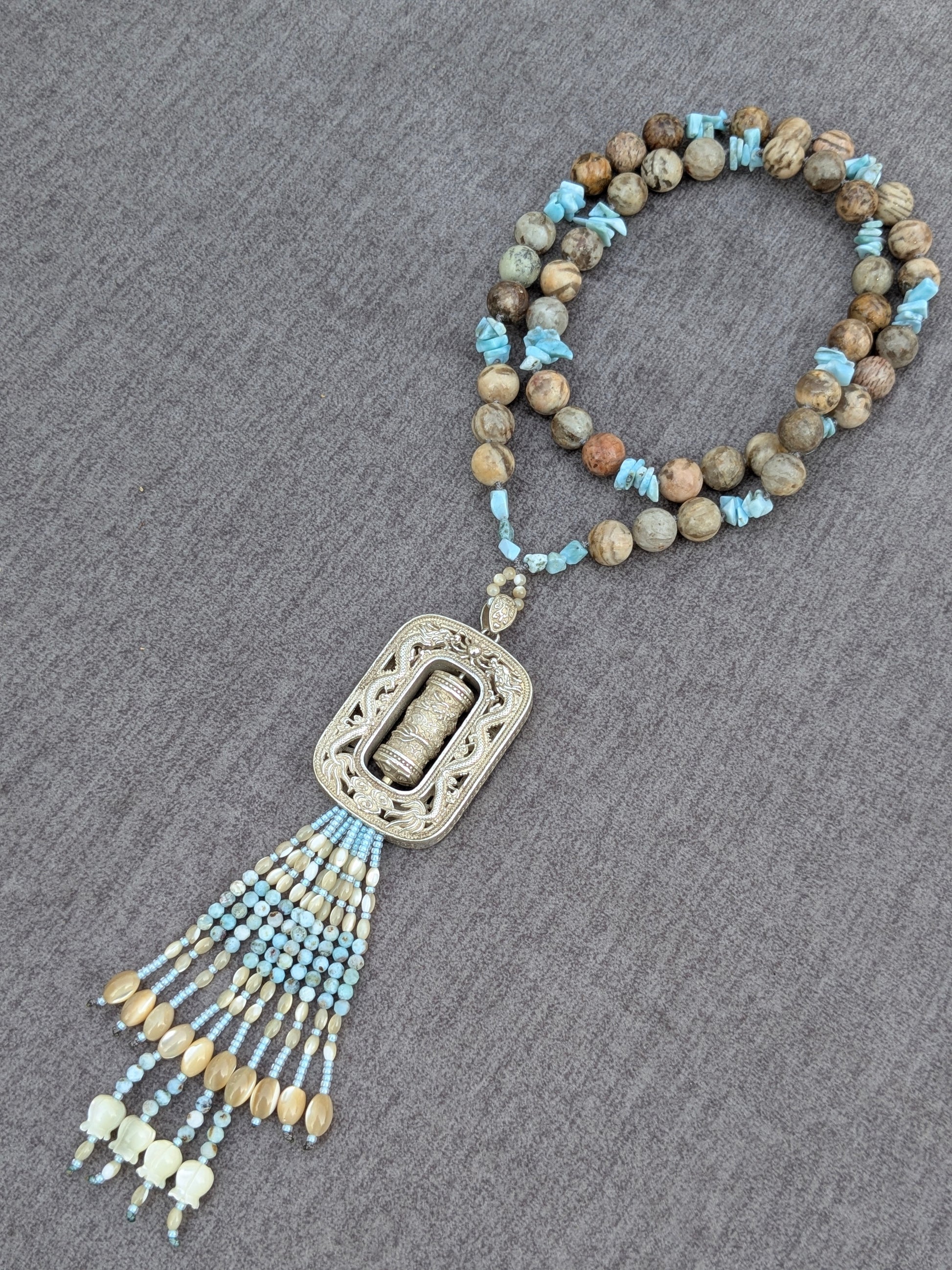 Vue rapprochée du tassel Mani, clochettes de nacre sculptées
