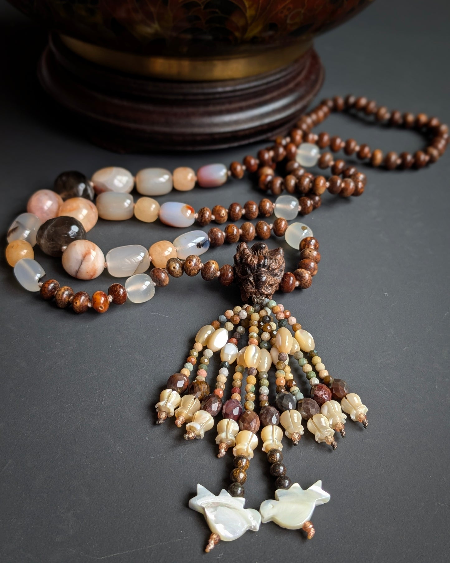 Mala Naga noué, vue d'ensemble avec perle du gourou tête de dragon et tassel, sur une potiche ancienne