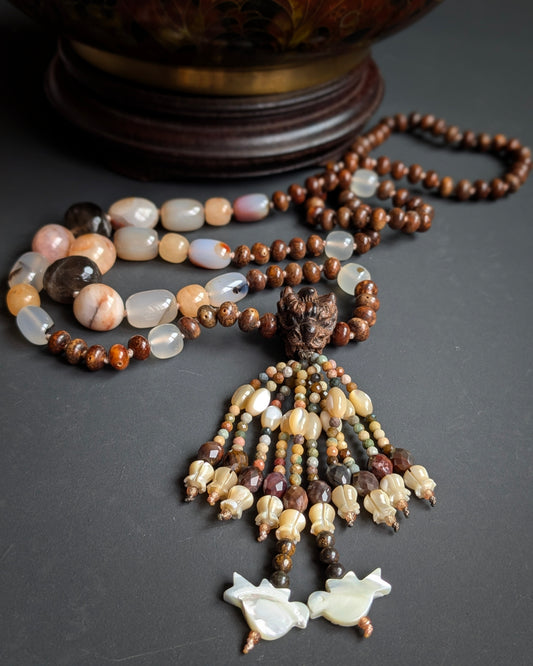 Mala Naga noué, vue d'ensemble avec perle du gourou tête de dragon et tassel, sur une potiche ancienne