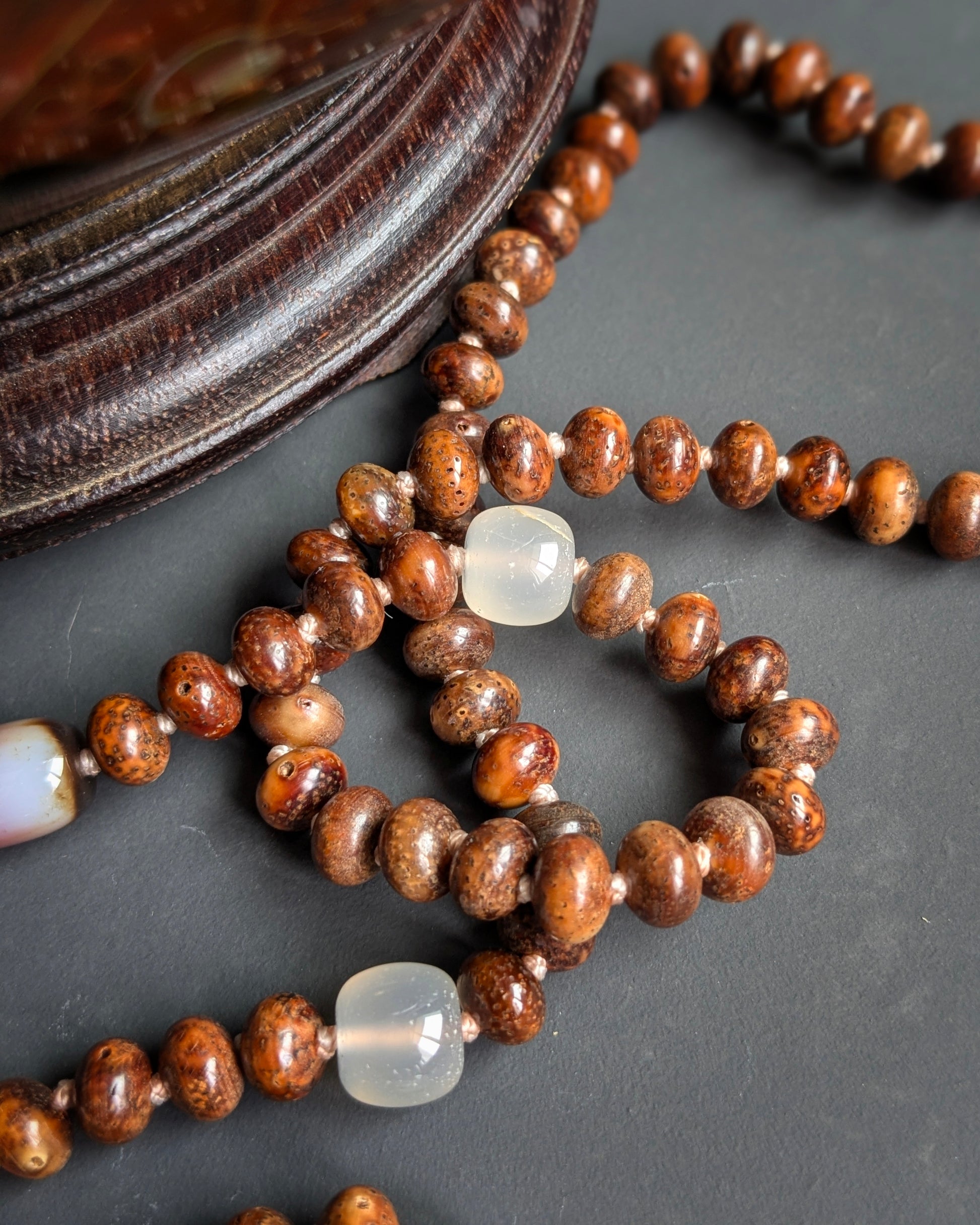 Détail des perles de starmoon bodhi patiné et d'agate blanche du mala Naga