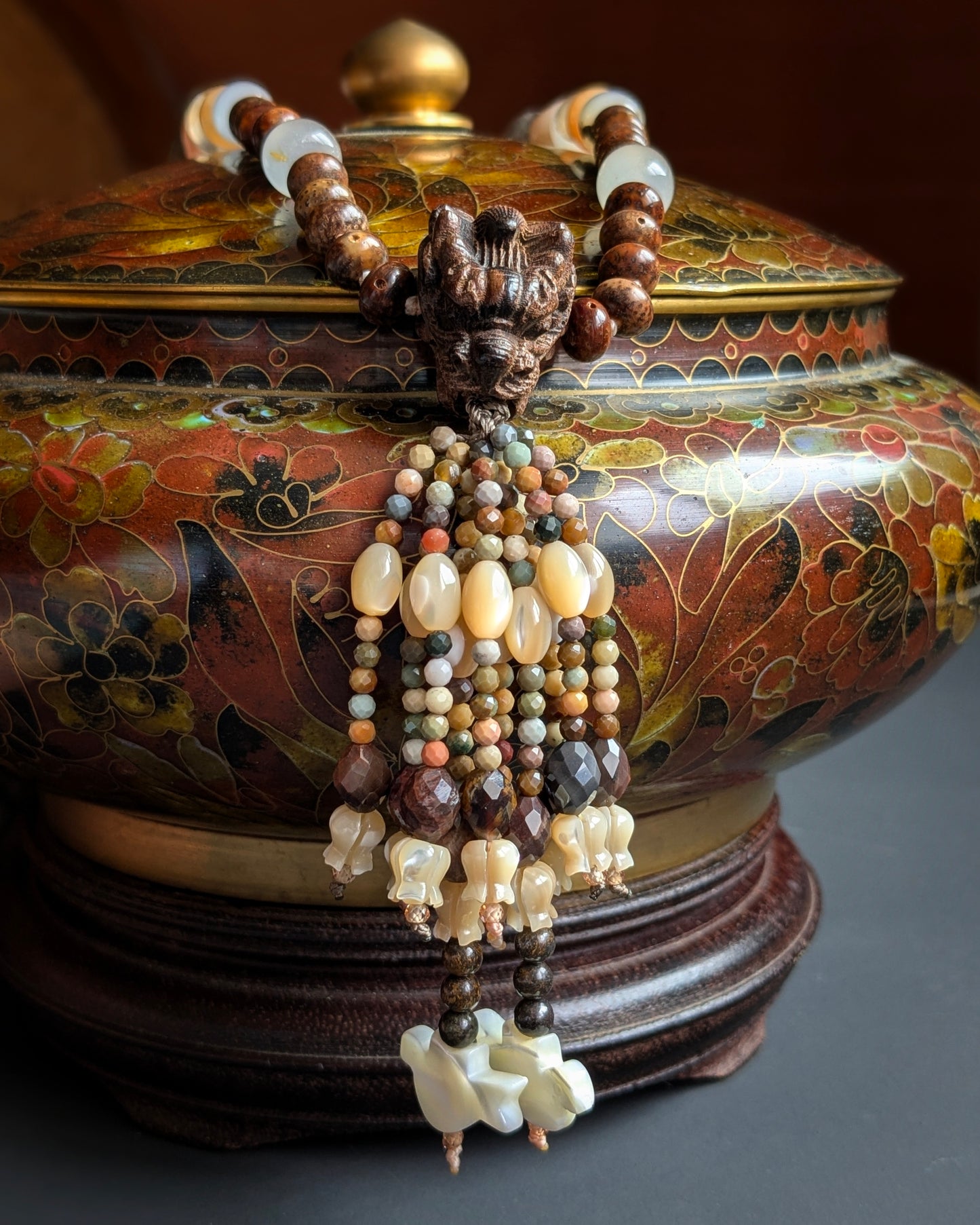Tassel du mala Naga suspendu sur une potiche ancienne, pierre de soleil et agates facettées