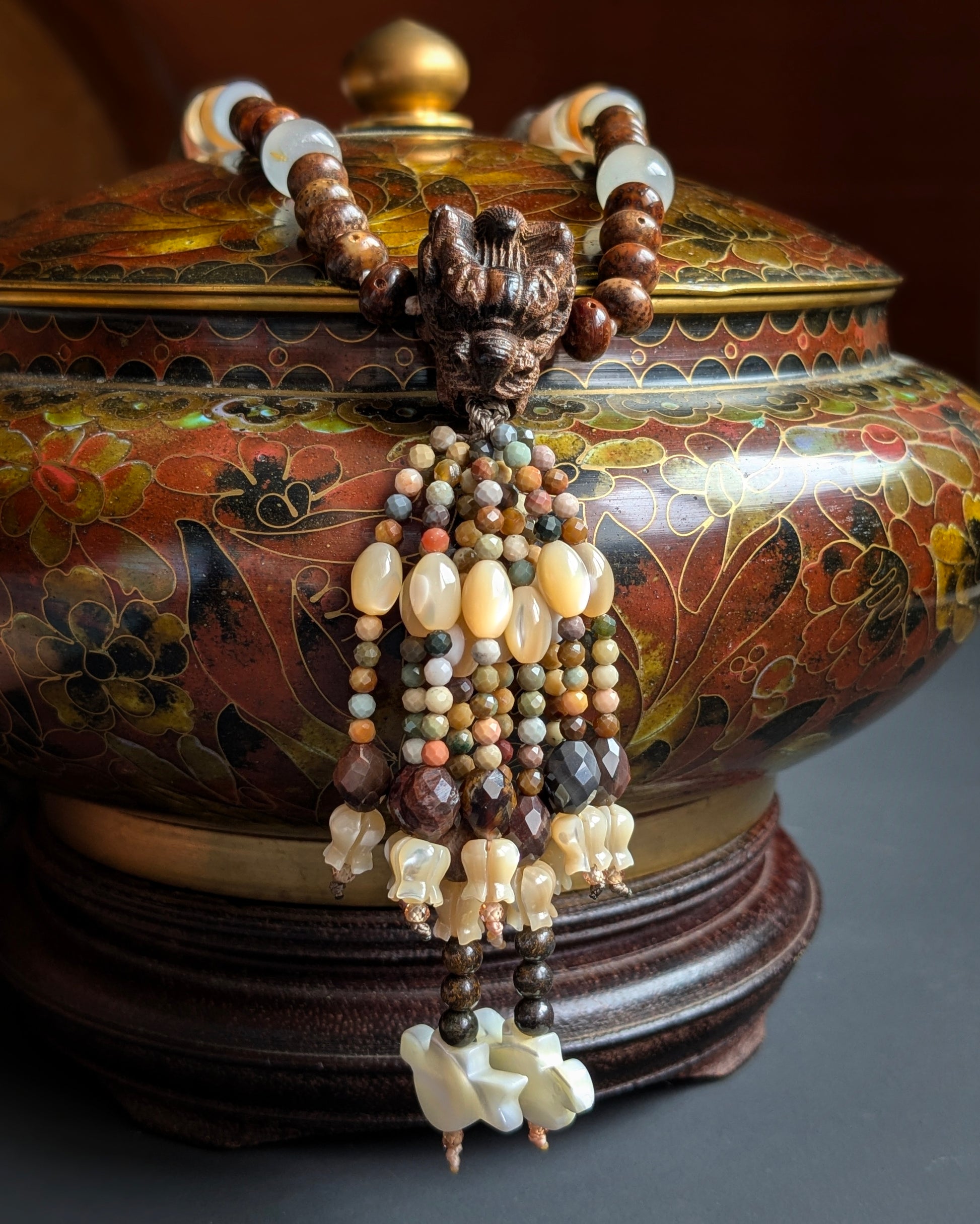 Tassel du mala Naga suspendu sur une potiche ancienne, pierre de soleil et agates facettées