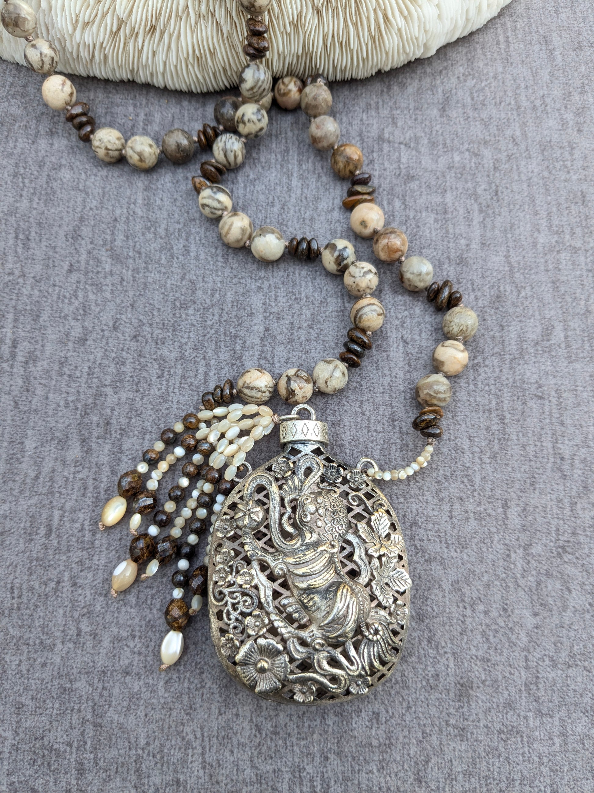 Vue d'ensemble du collier Shishi noué, longueur et pendentif visibles sur corail blanc