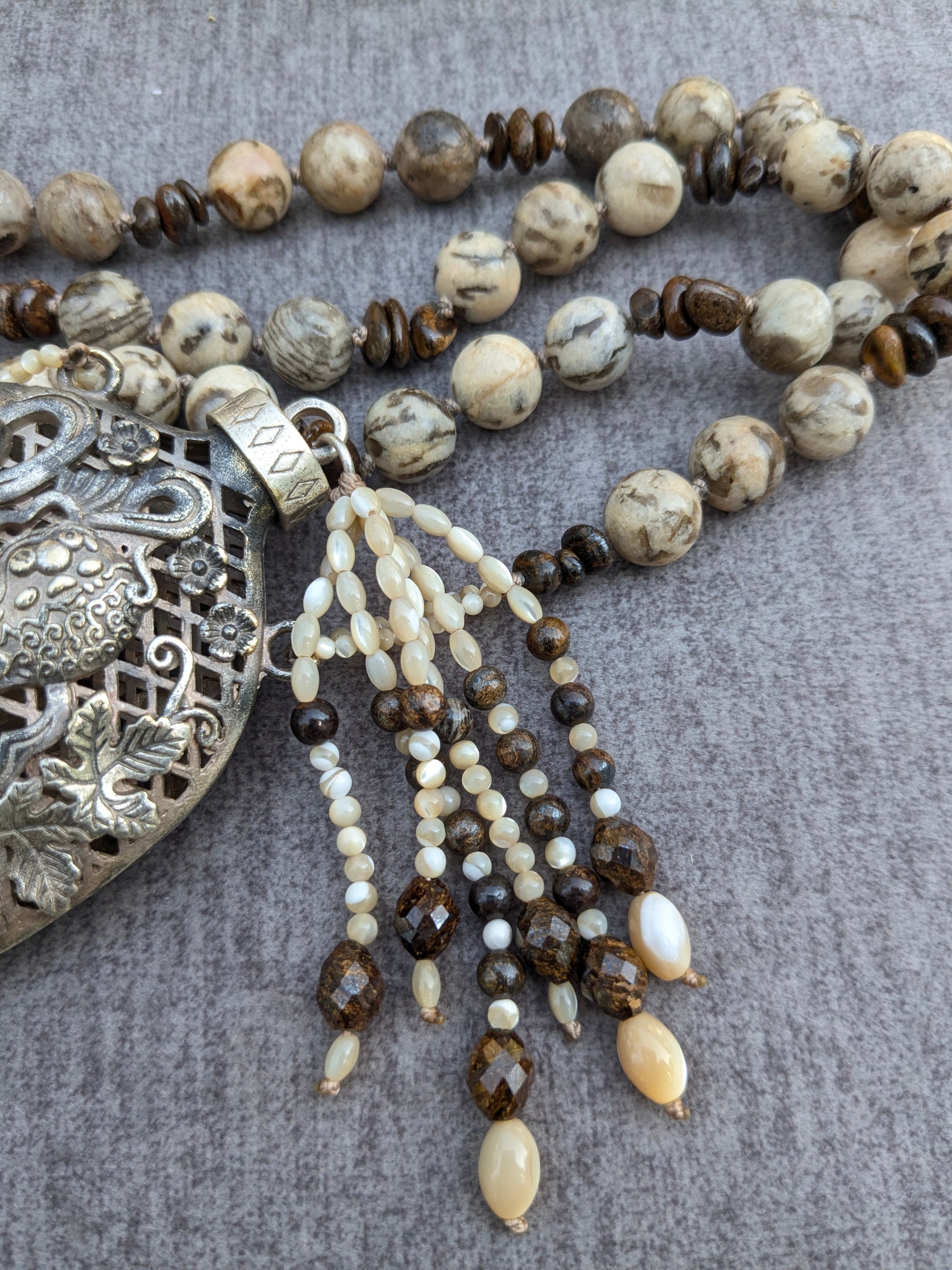 Détail du pendentif flacon Shishi et des pampilles nacre de trochus et bronzite fixées au bouchon