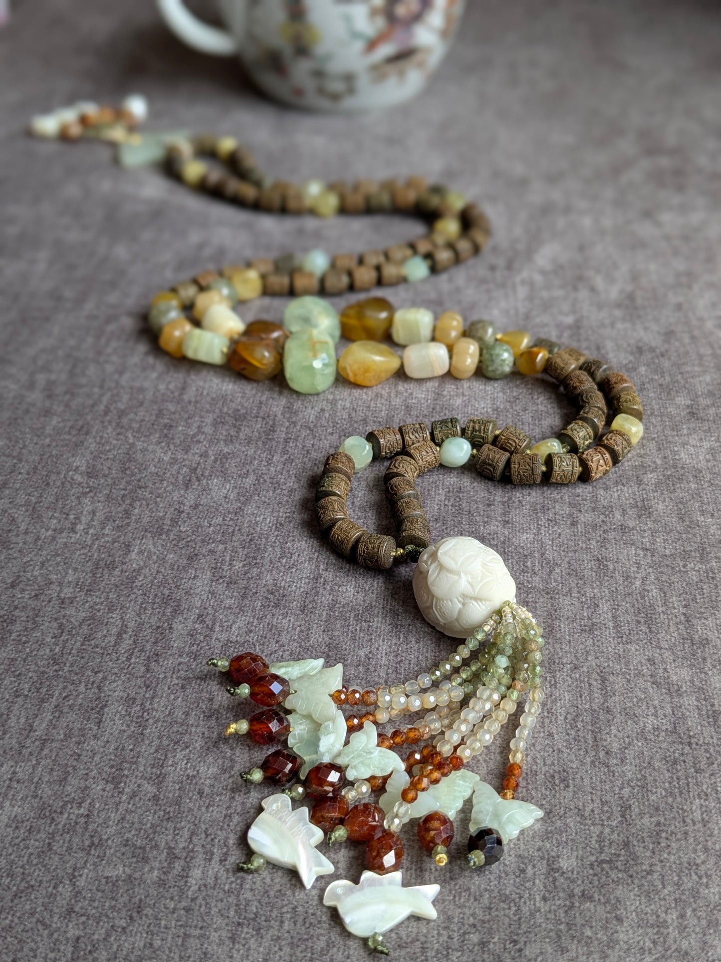 Mala Xuan Wu noué, perle du gourou et tassel visibles, avec tasse en porcelaine