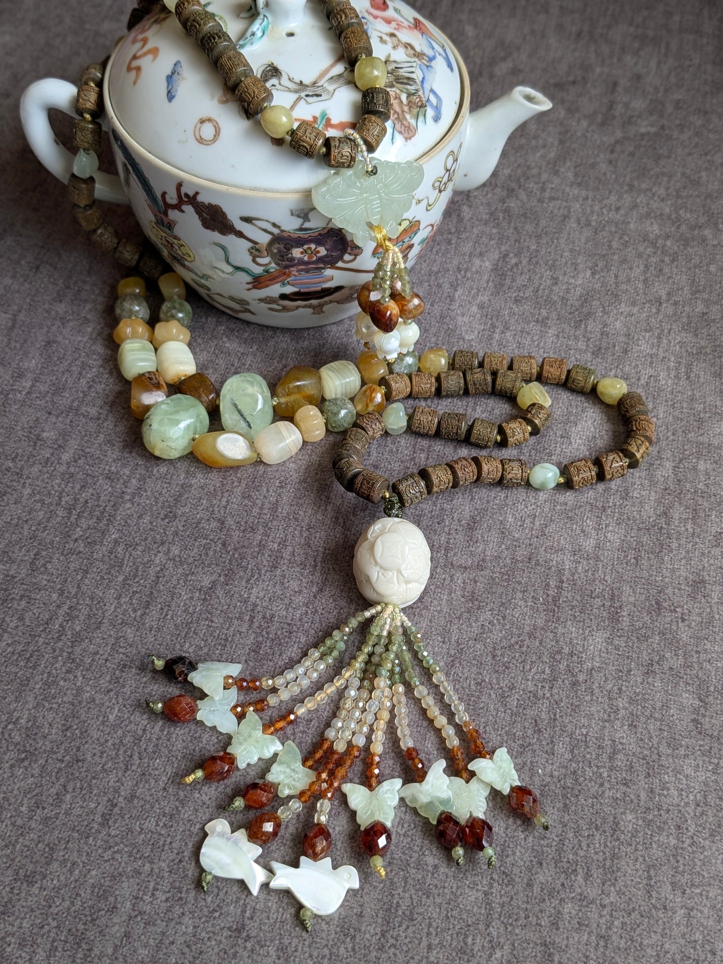 Mala Xuan Wu noué en 108 perles, vue d'ensemble avec les deux pendentifs sur une théière en porcelaine