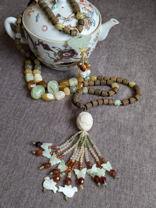 Mala Xuan Wu noué en 108 perles, vue d'ensemble avec les deux pendentifs sur une théière en porcelaine