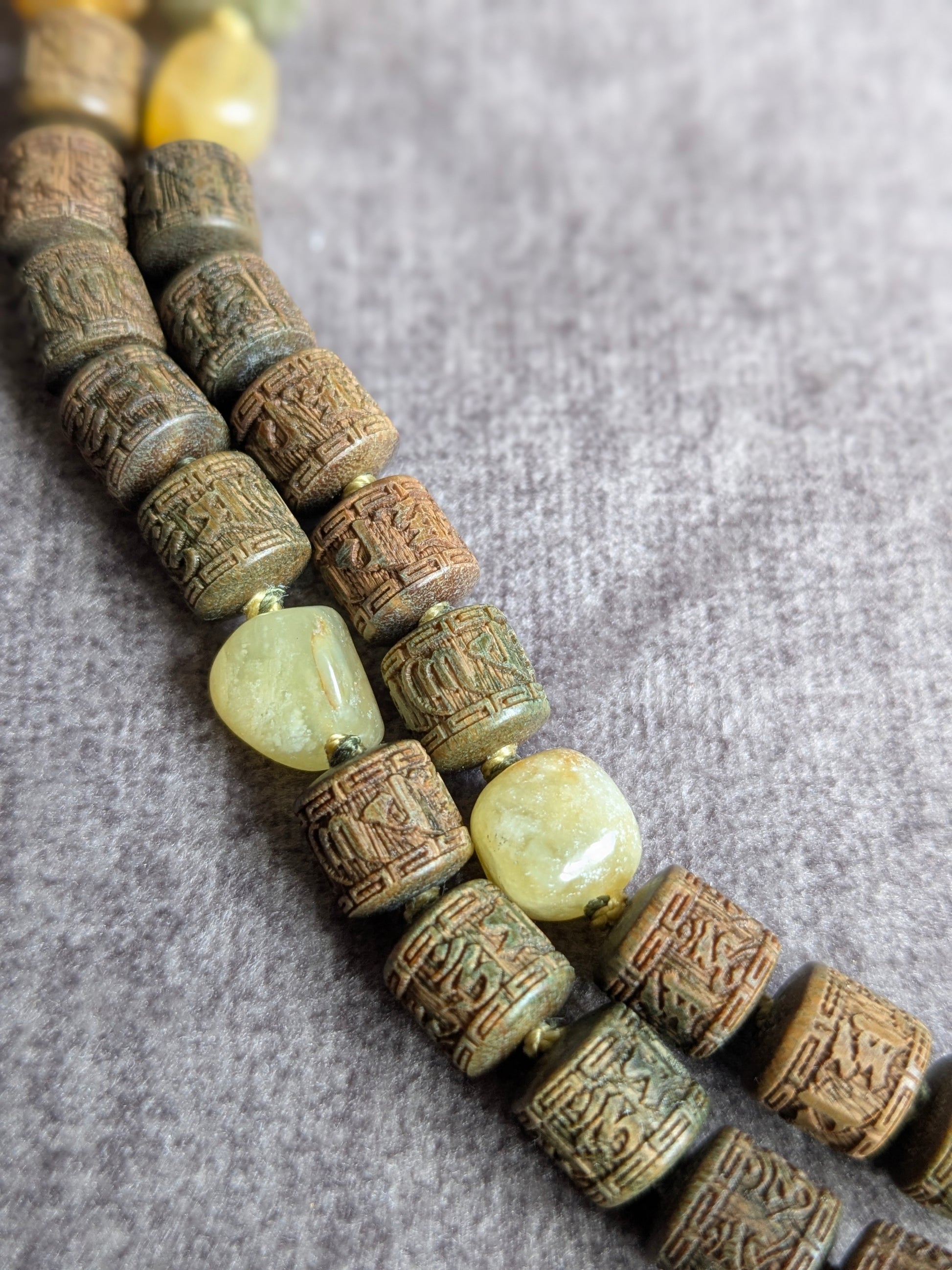 Détail des perles de bois de santal ciselées du mantra Om Mani Padme Hum, mala Xuan Wu