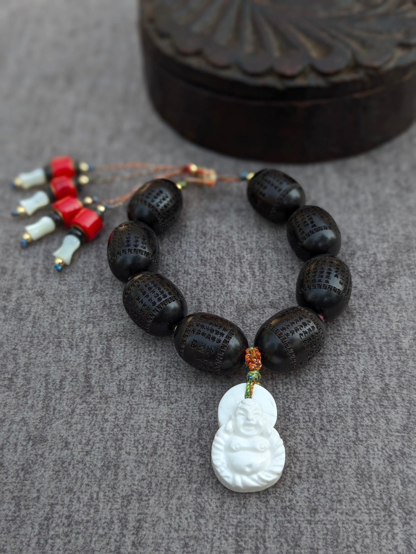 Bracelet Norbu Mudra, perles ovales en santal noir gravées du Sûtra du Cœur avec pendentif Budai en coquillage blanc et pampilles pierre rouge et nacre
