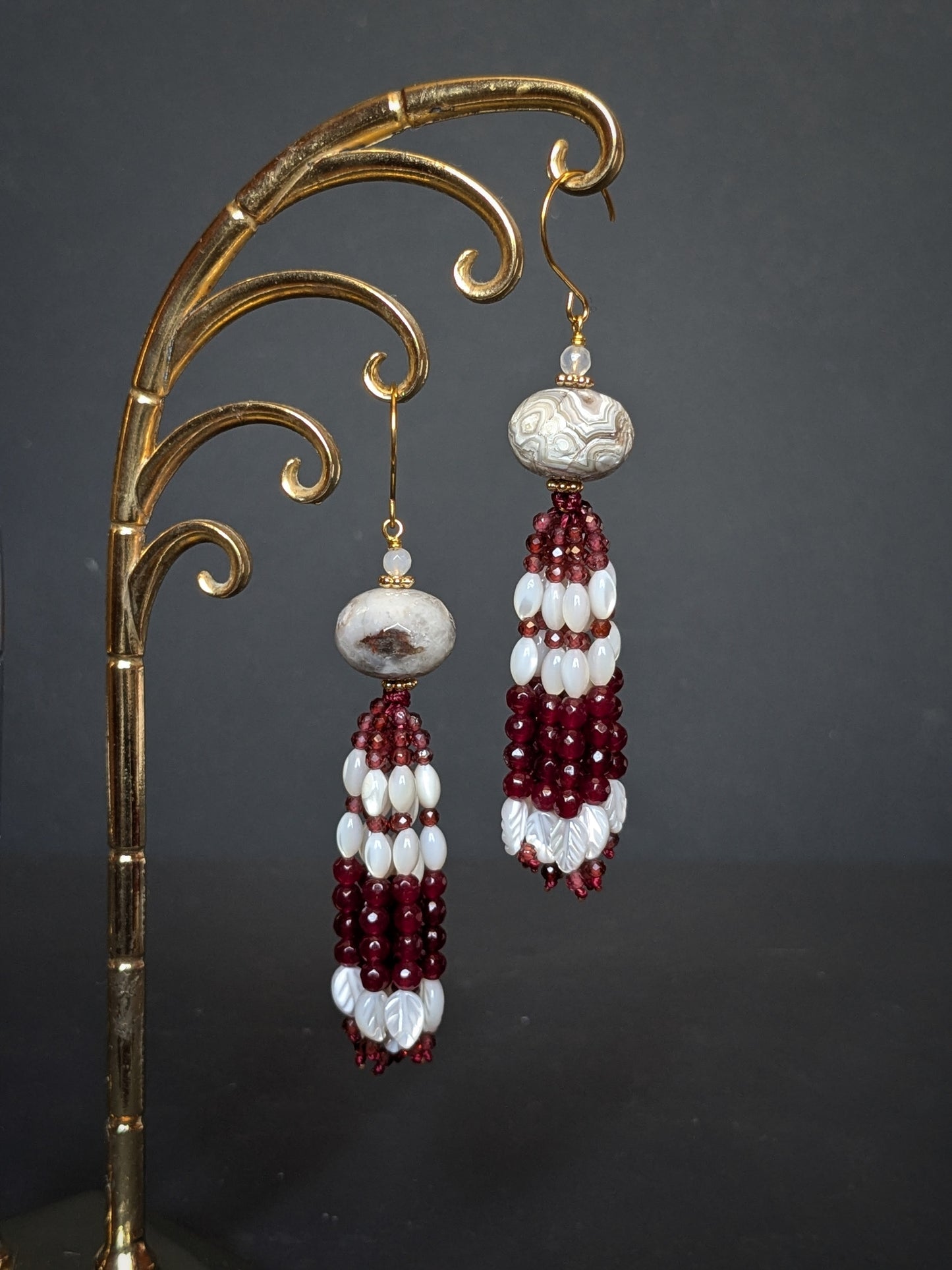 Pendants d'oreilles Vani posés sur un présentoir, agate mexicaine et tassel de grenat et nacre blanche
